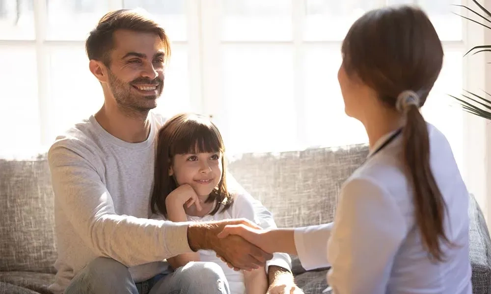 Father and daughter greeting a healthcare provider during a well visit, illustrating Pediatric Home Visits.