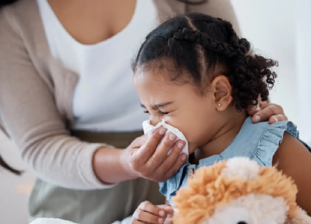 Mother cleaning her child’s nose with a tissue at home in Katy, TX, illustrating seasonal allergies in children and pediatric care